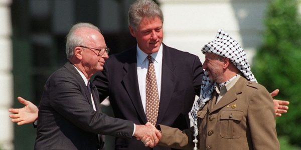 Israeli Prime Minister Yitzhak Rabin, left, and PLO chairman Yasser Arafat, right, shake hands as President Bill Clinton presides over the ceremony marking the signing of the 1993 peace accord between Israel and the Palestinians on the White House lawn, Sept. 13, 1993. (AP Photo/Ron Edmonds)